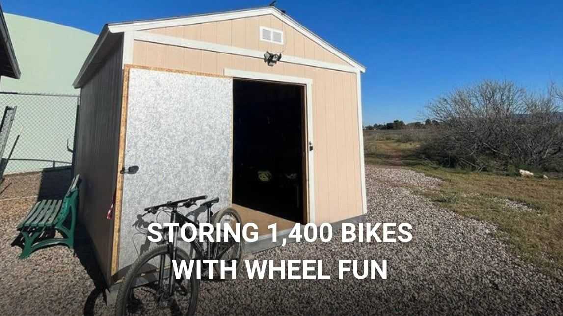 This is a shed that is being used for bike storage and it has a bike parked out in front of the building.
