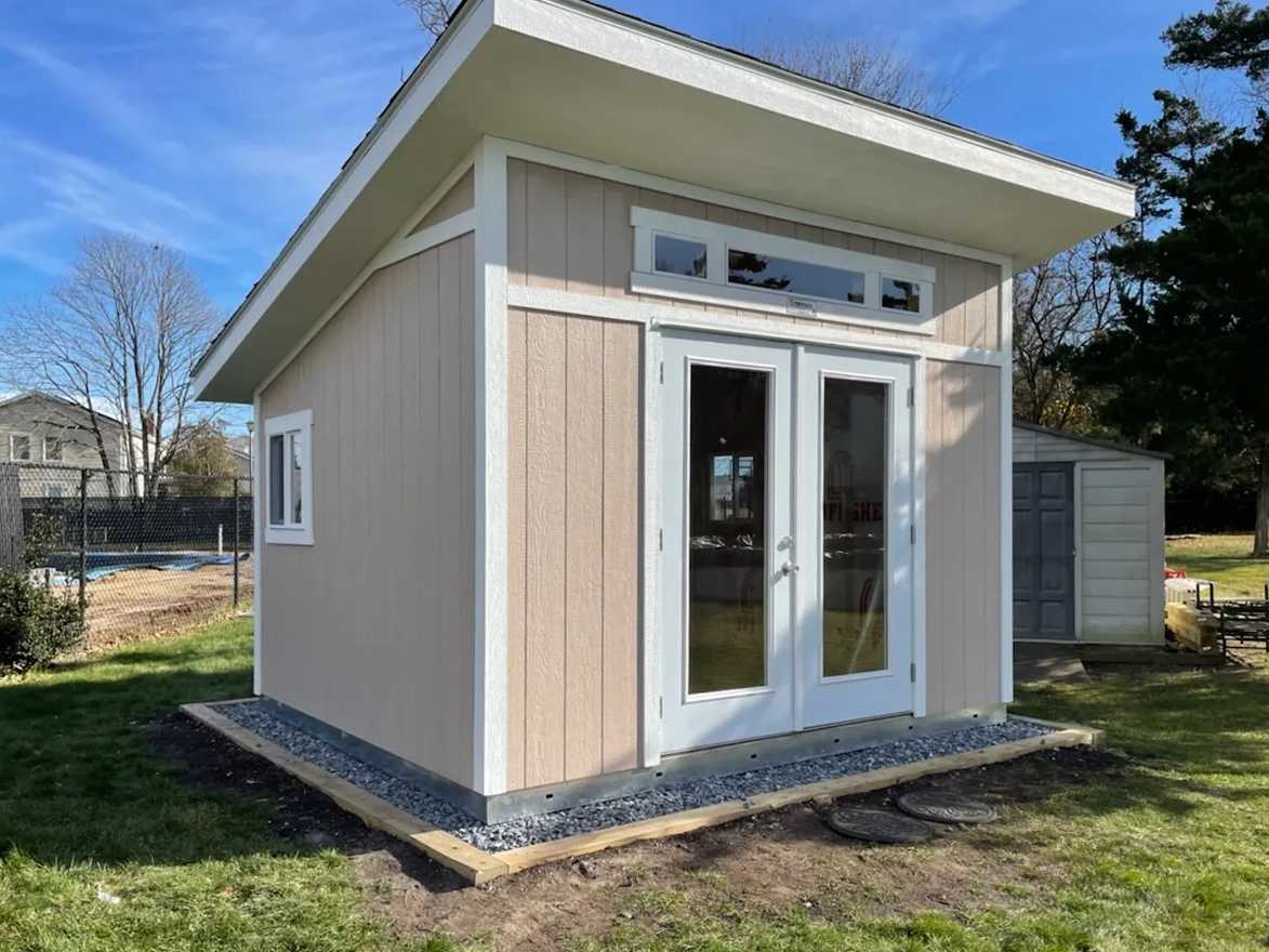 Light brown and white lean to studio in backyard