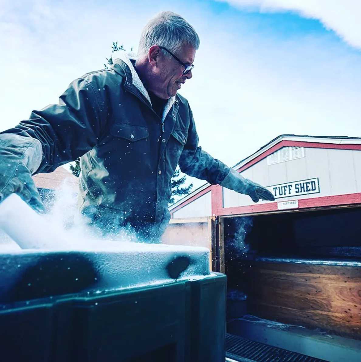 Exterior photo of Frozen Dead Guy caretaker Brad Wickham putting ice into the Tuff Shed