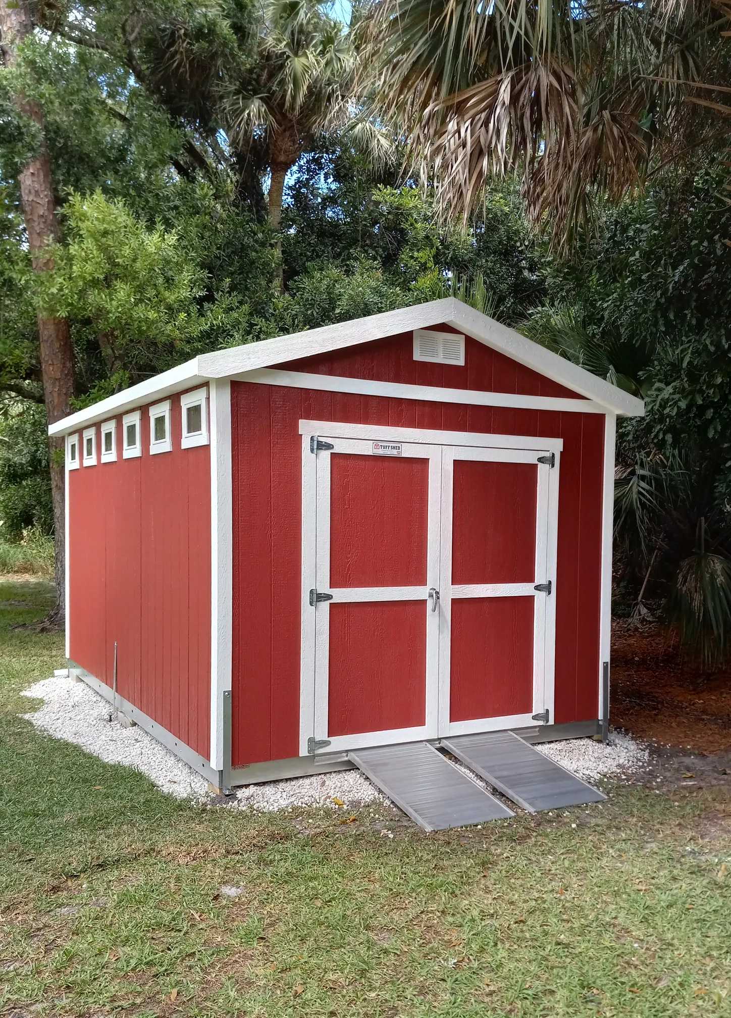 Red and white shed in a backyard with heavy duty steel ramps