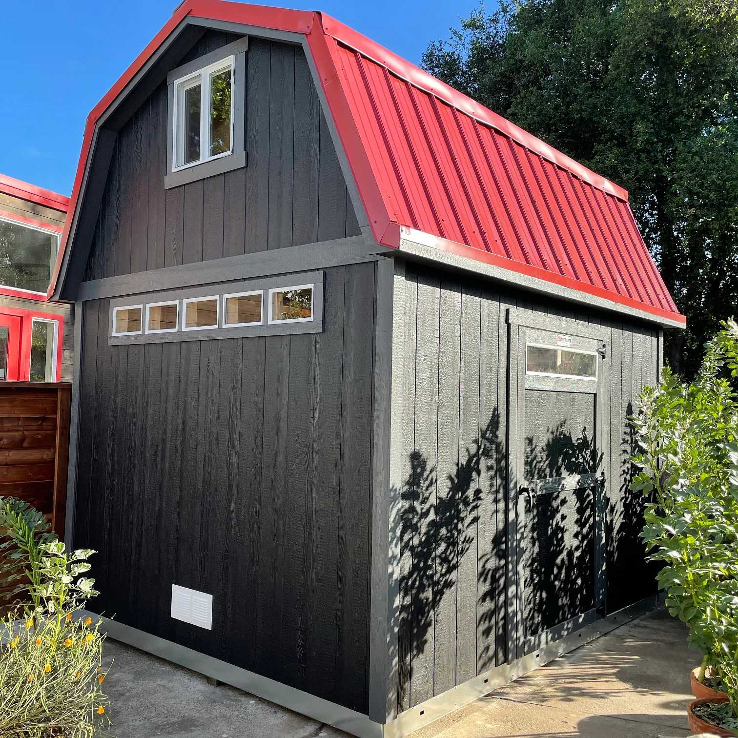 black and red barn in a garden