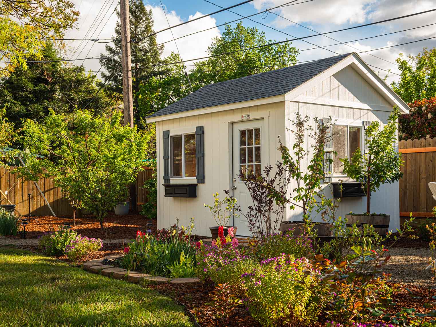 a white shed in the blooming garden