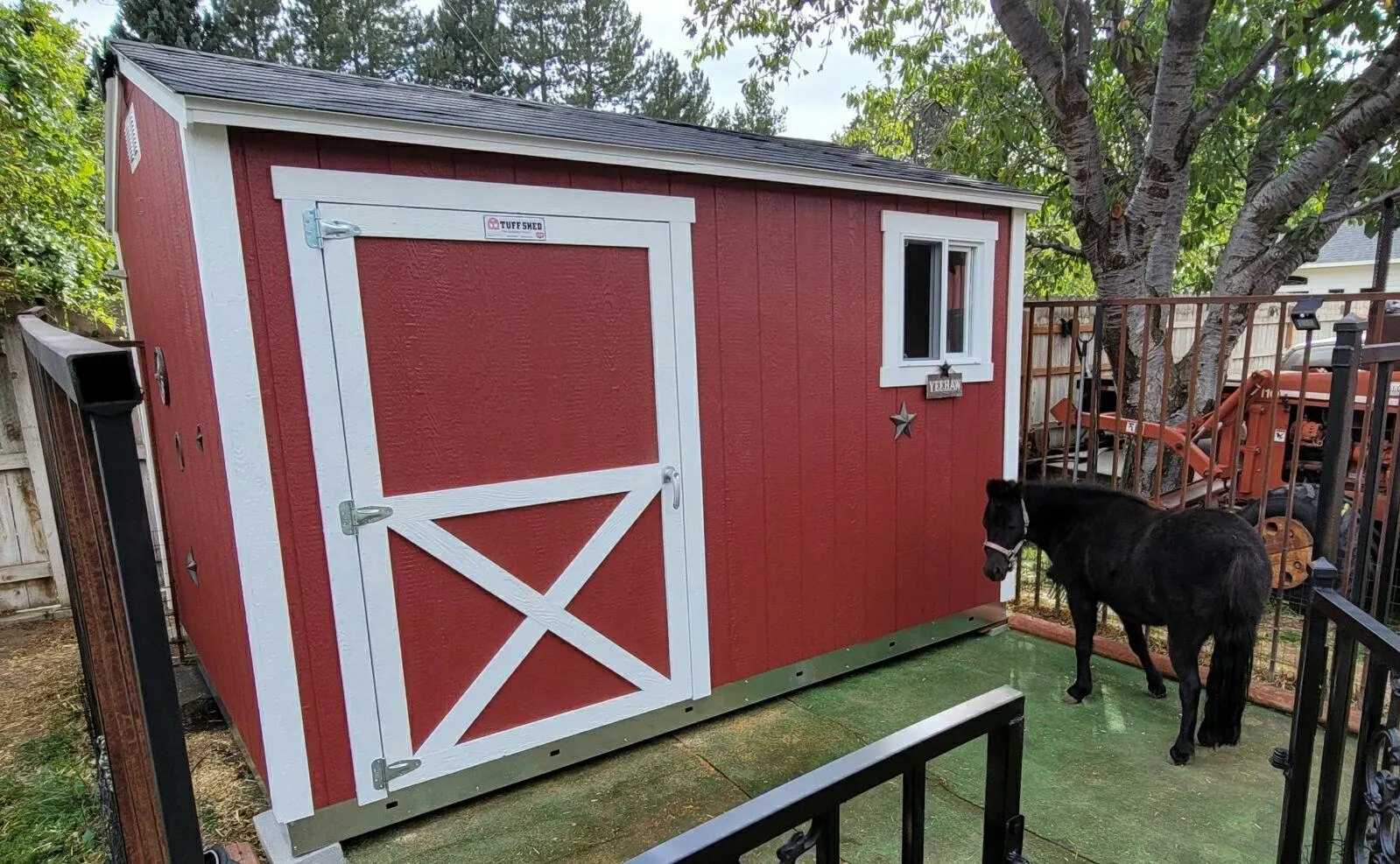 Red and white shed with a small horse next to it