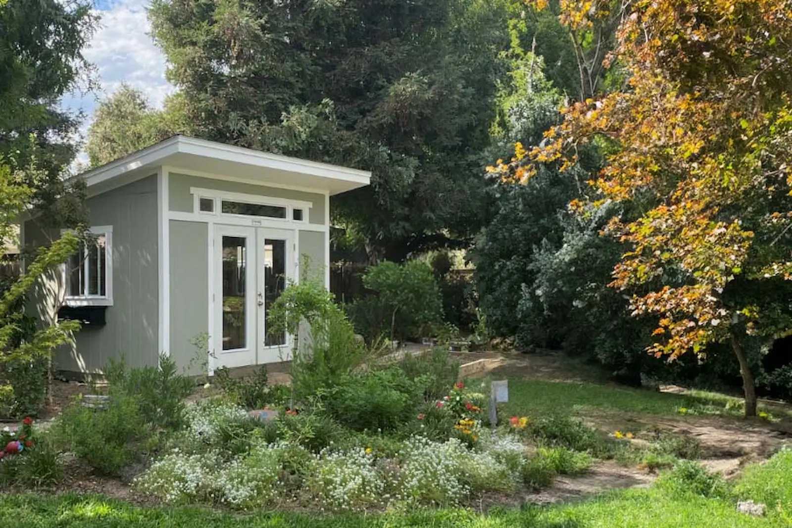Green lean-to building in the garden with glass doors and windows