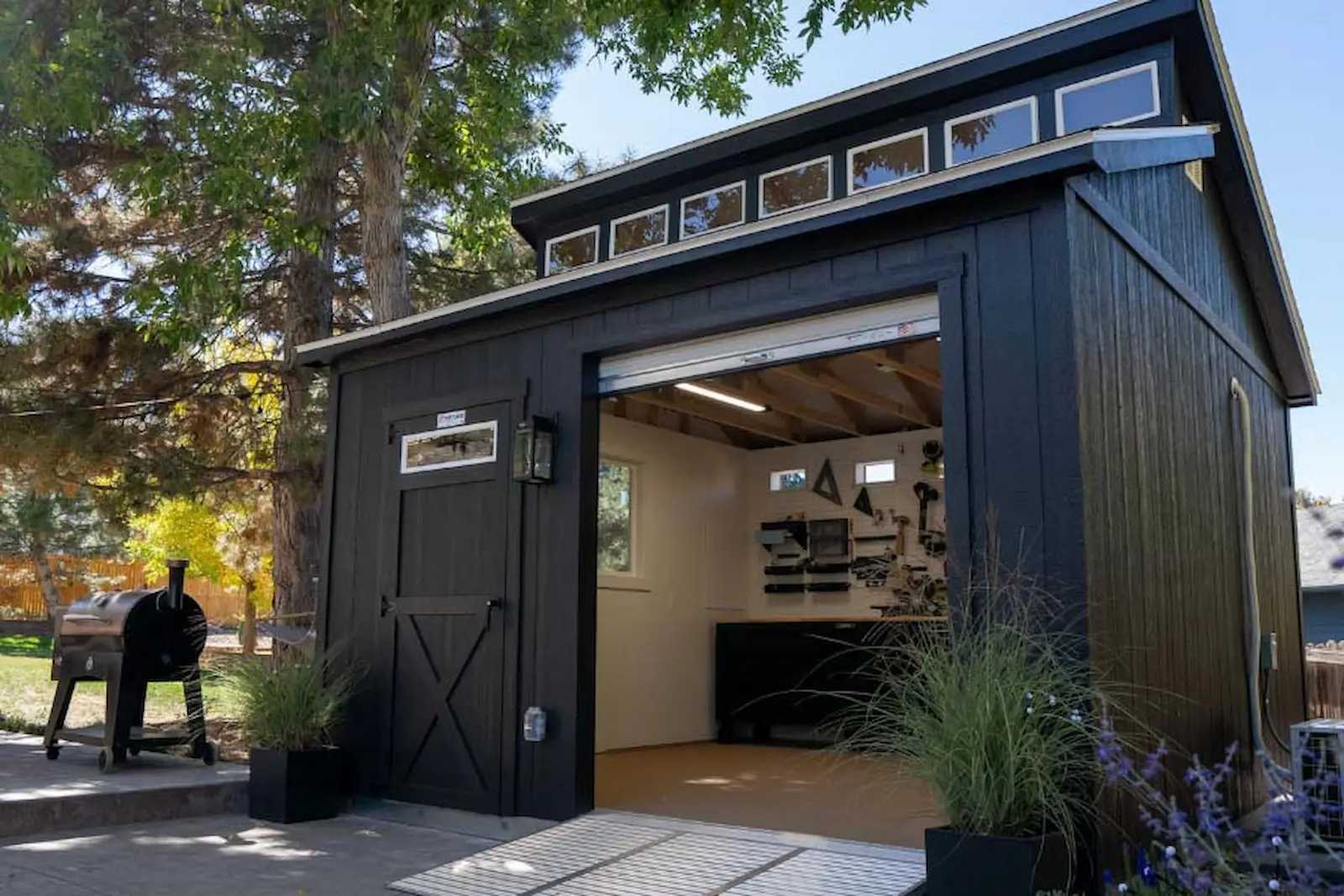 Black tall ranch with clerestory roof upgrade and overhead door in backyard