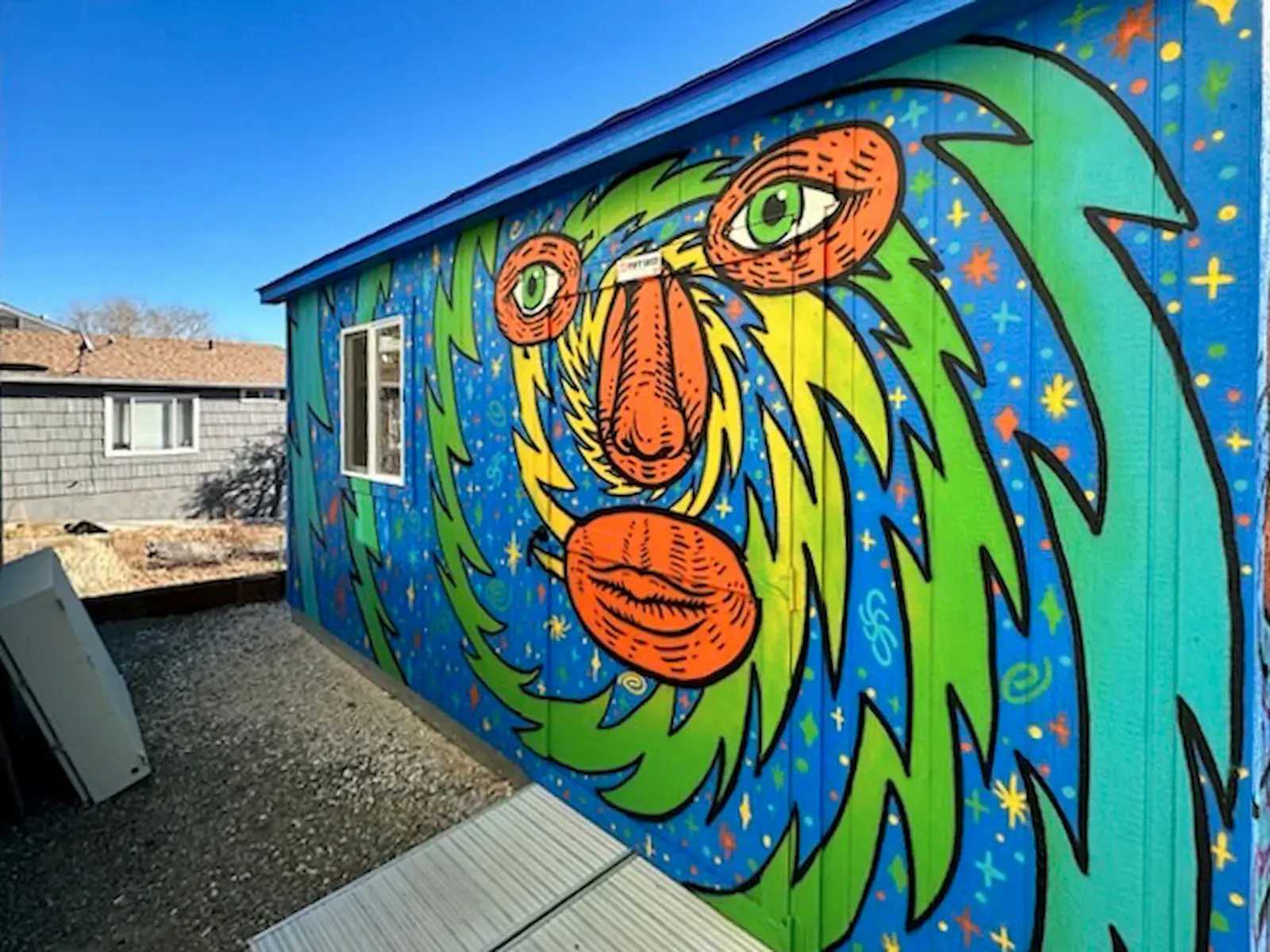 Side of a bright blue shed with a face mural