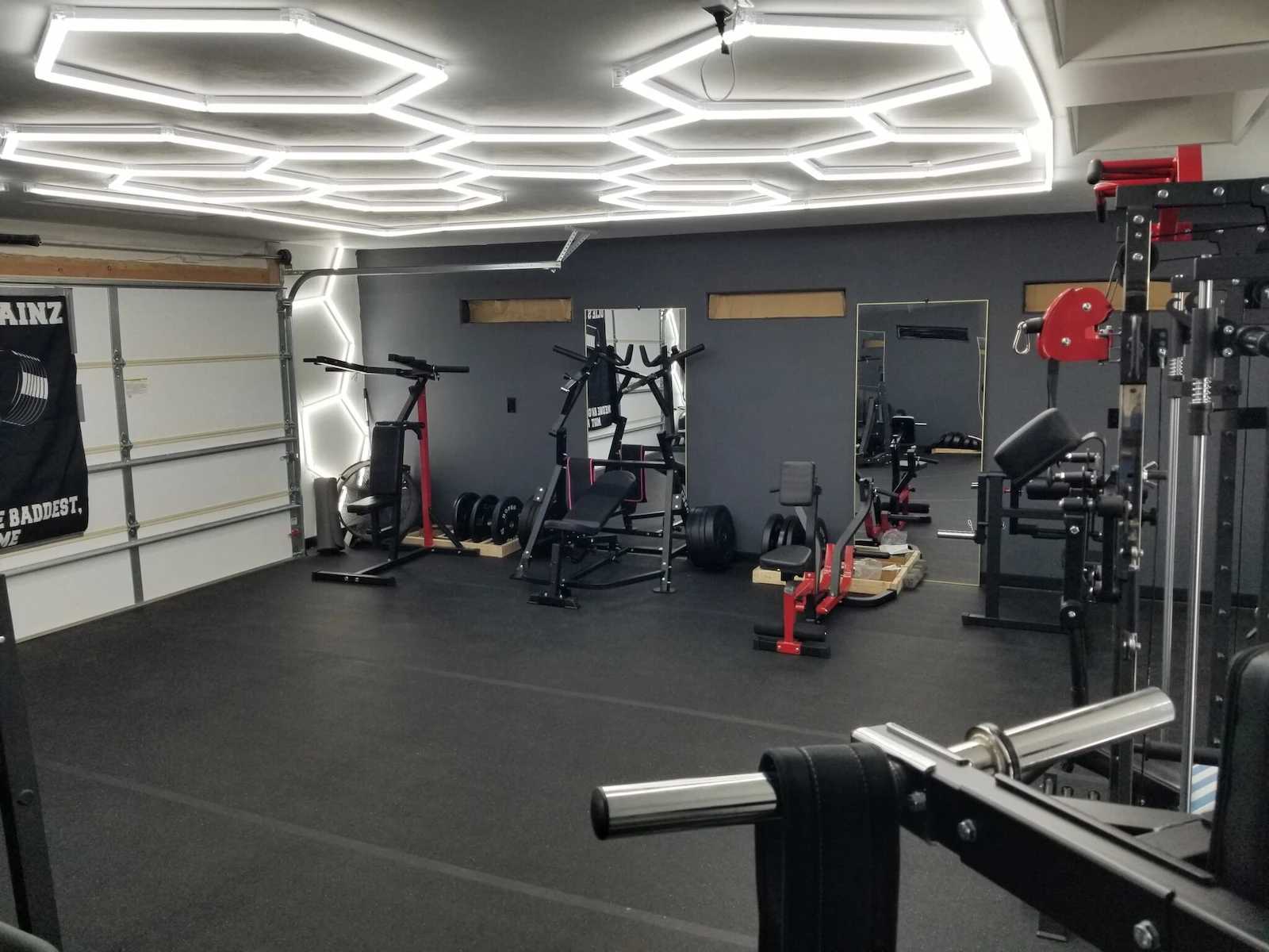 Interior of Oliver's home gym garage with weight machines and lights
