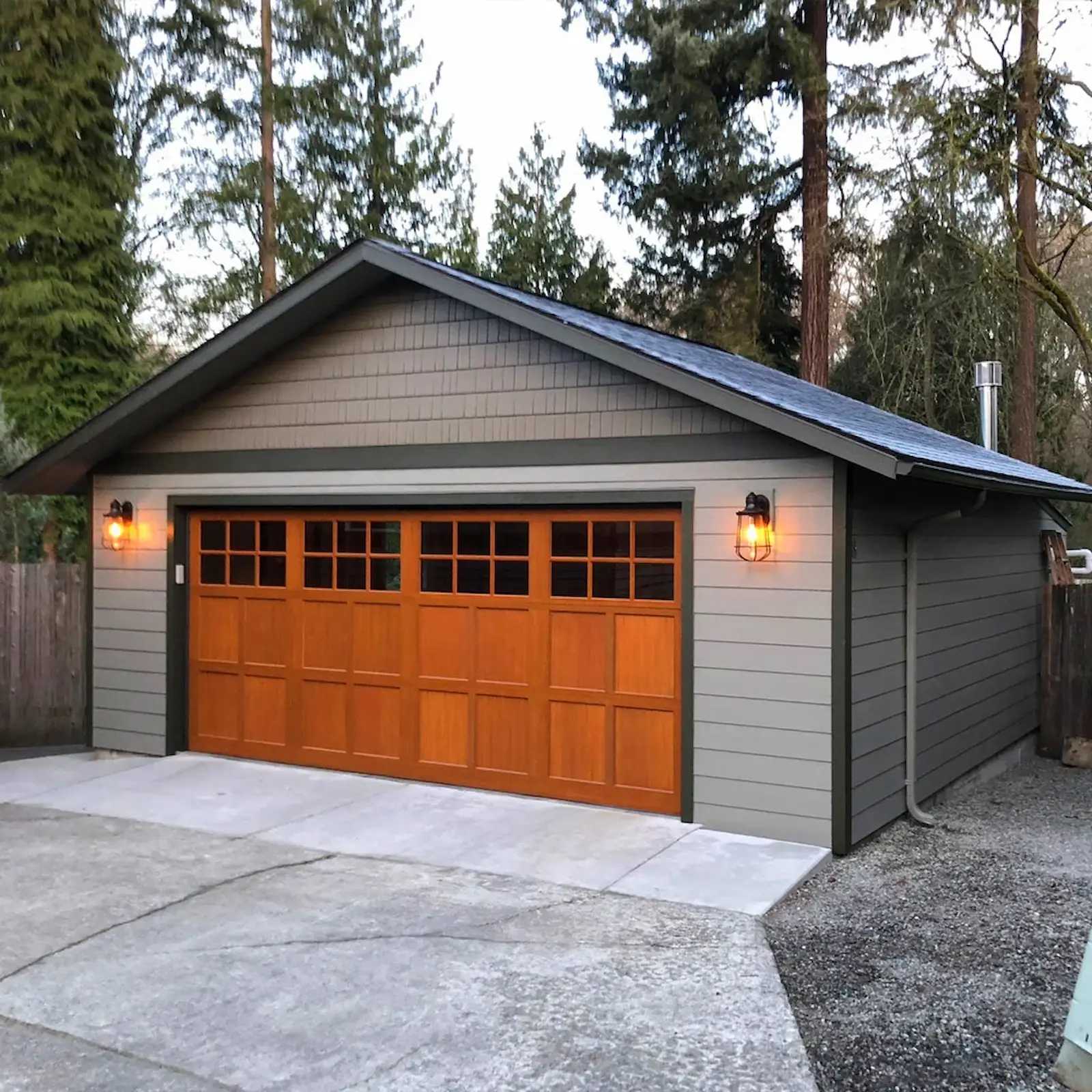 Gray Premier Pro Ranch Garage with wooden door and lights on a concrete pad