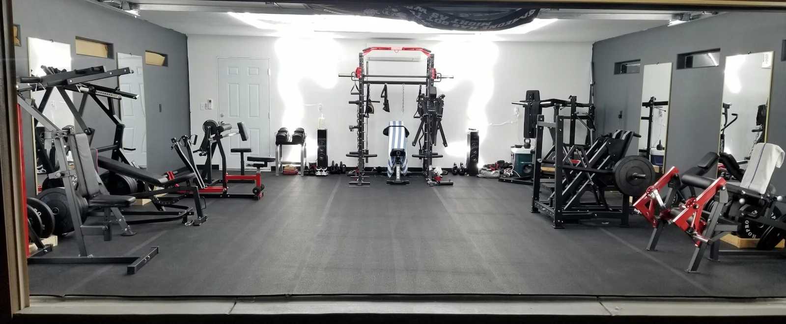 Interior of Oliver's home gym garage with weight machines and squat rack