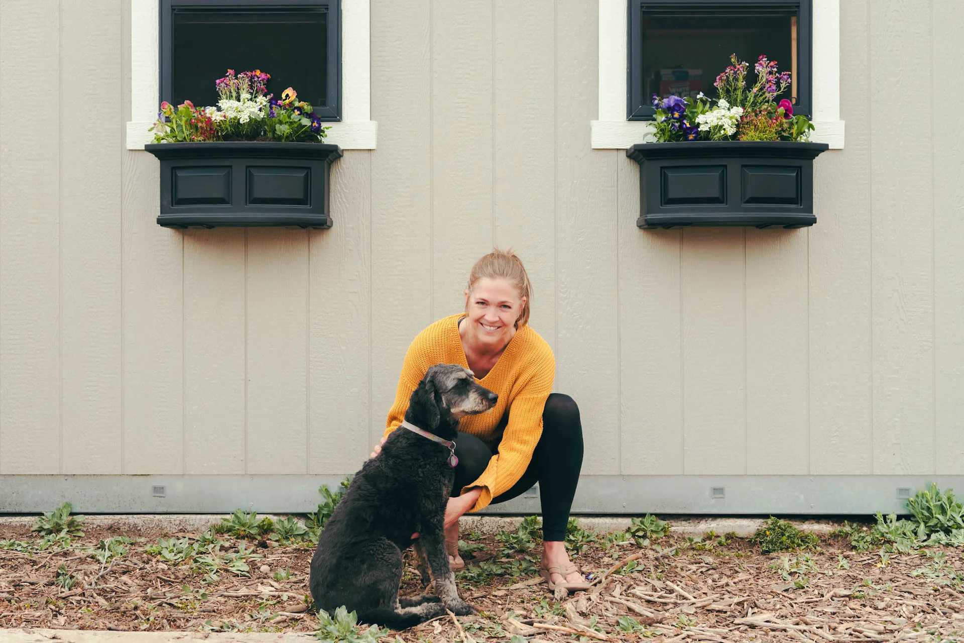 Karen and dog in front of Premier Tall Barn with flower boxes