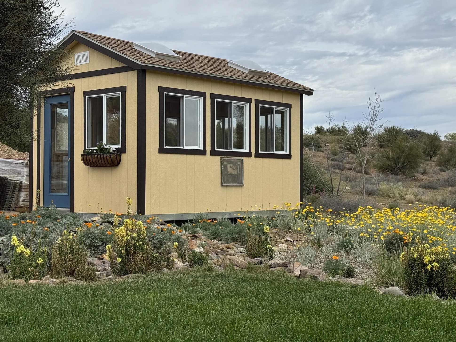 Yellow and black shed with skylights in a field of flowers