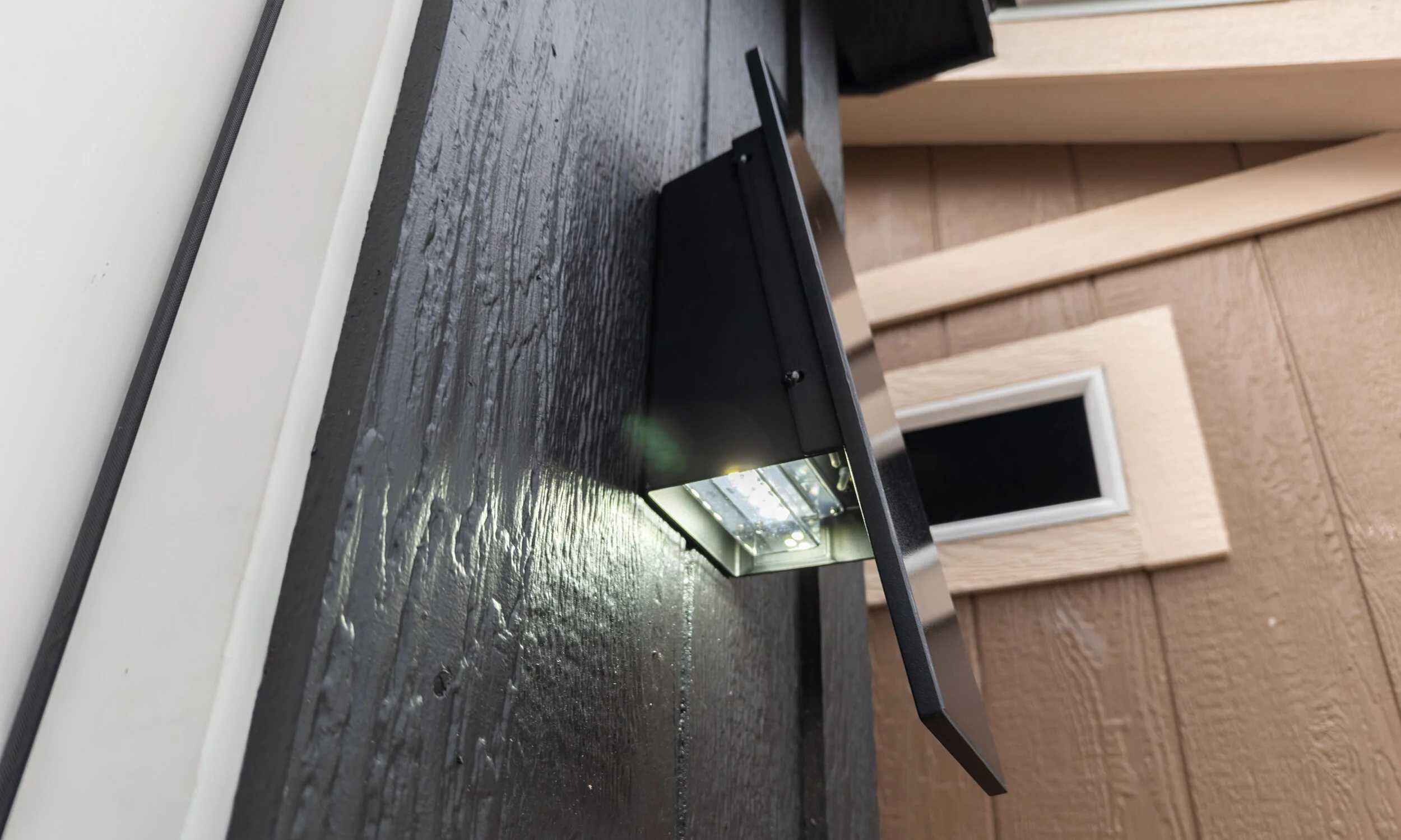 Outdoor LED light fixture on a textured dark wall, illuminating the surface