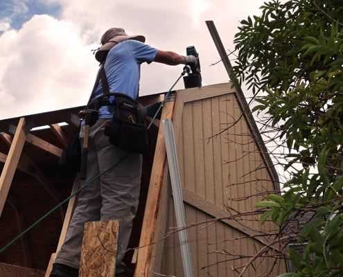 Exterior, Tuff Shed certified installer on ladder using nail gun to install truss