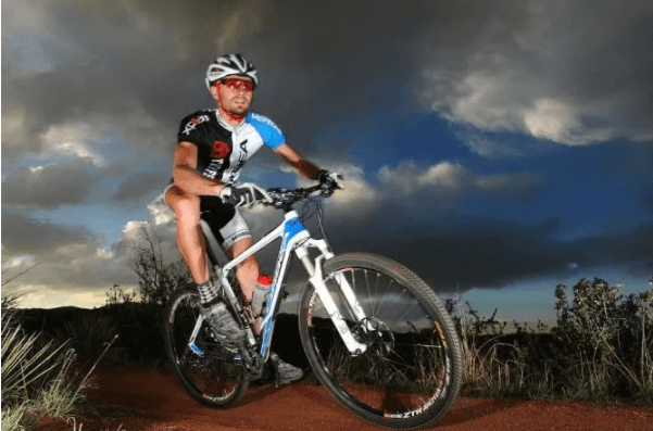 Mountain biker in Tuff Shed uniform on bike on trail at dusk