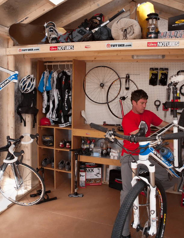 Interior Tuff Shed Pro Sports Edition bike equipment on peg board and man working on bike