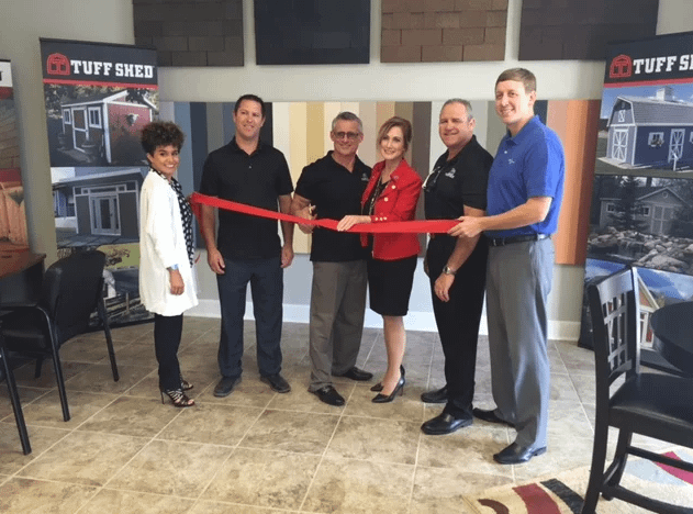 Interior of store with 6 people cutting a red ribbon in front of the Tuff Shed paint selection wall
