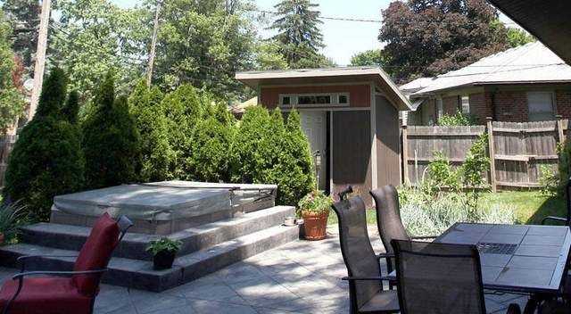 A Premier PRO Lean-To in a backyard next to a hot tub in front of fence