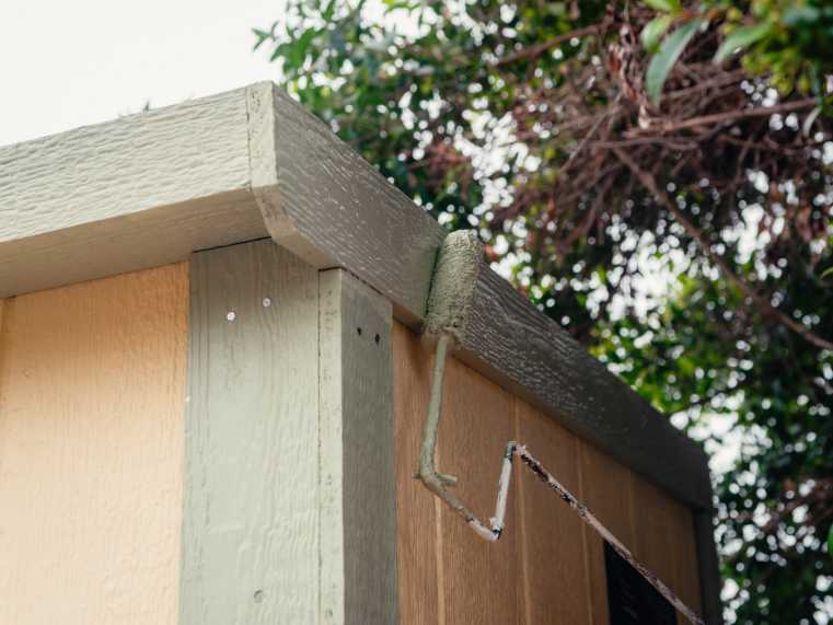 installer painting a trim of a shed