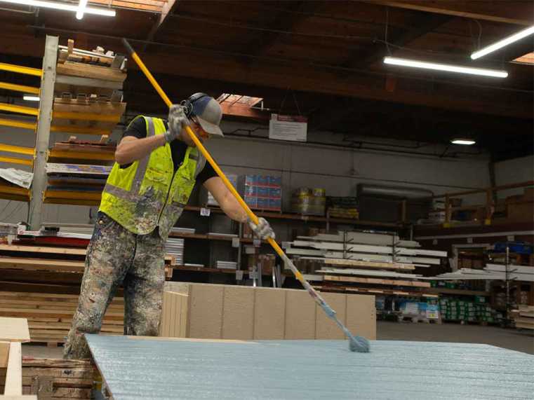 Factory worker applying a coat of blue paint by Glidden paint