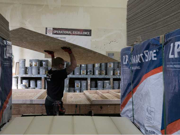 A factory worker caring sheet of plywood