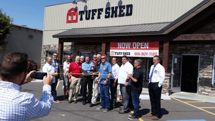 Exterior of Idaho Falls Tuff Shed location with 13 people cutting a yellow ribbon