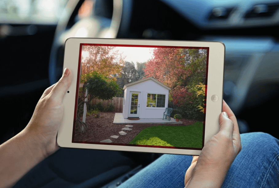 Person in a car looking at a shed on a tablet screen with their hands on either side of the screen