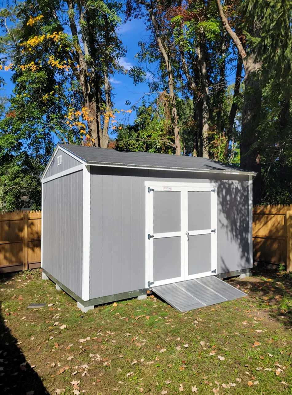 Grey and white barn in a backyard with steel ramps