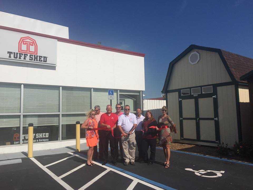 Exterior of Fort Myers Tuff Shed location 8 people standing in parking lot in front of Pro Tall Barn cutting a red ribbon as they stand in a handicapped parking space