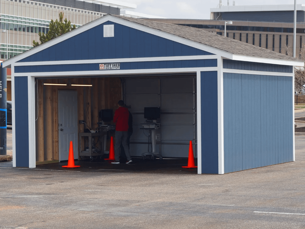 A blue Premier Ranch Garage exterior with installer within setting up orange cones