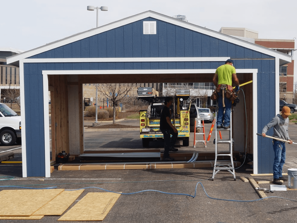 A Premier Ranch Garage Blue back with doors open and three installers one on ladder